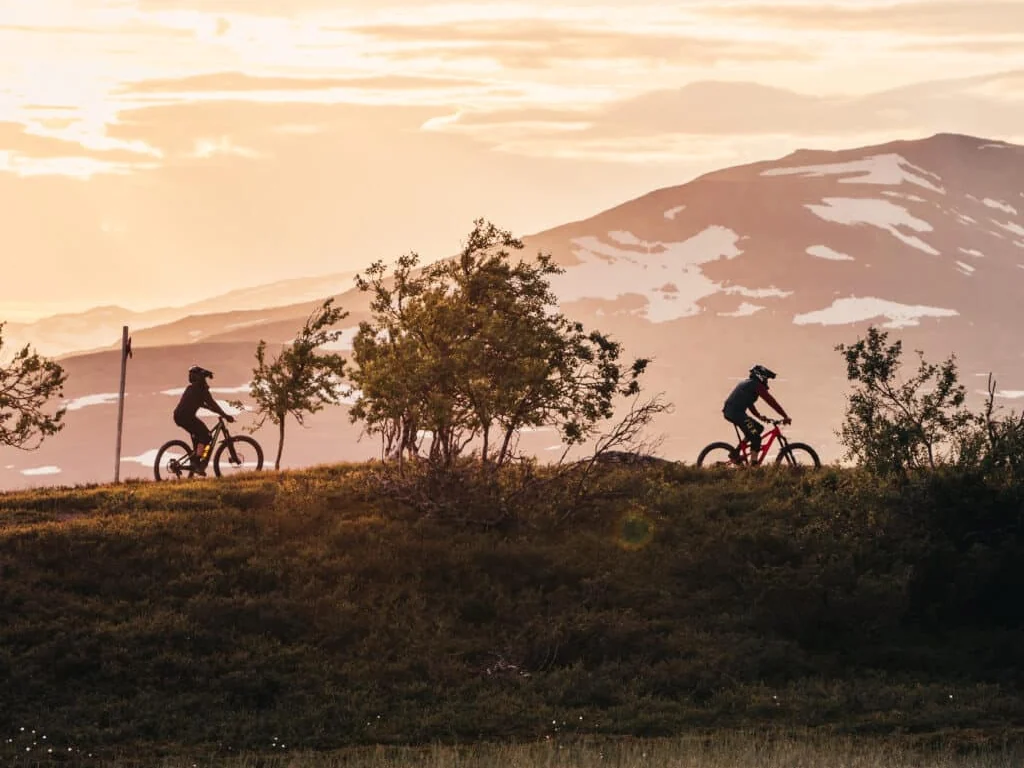 Cyklister i motljus mot fjällkammen