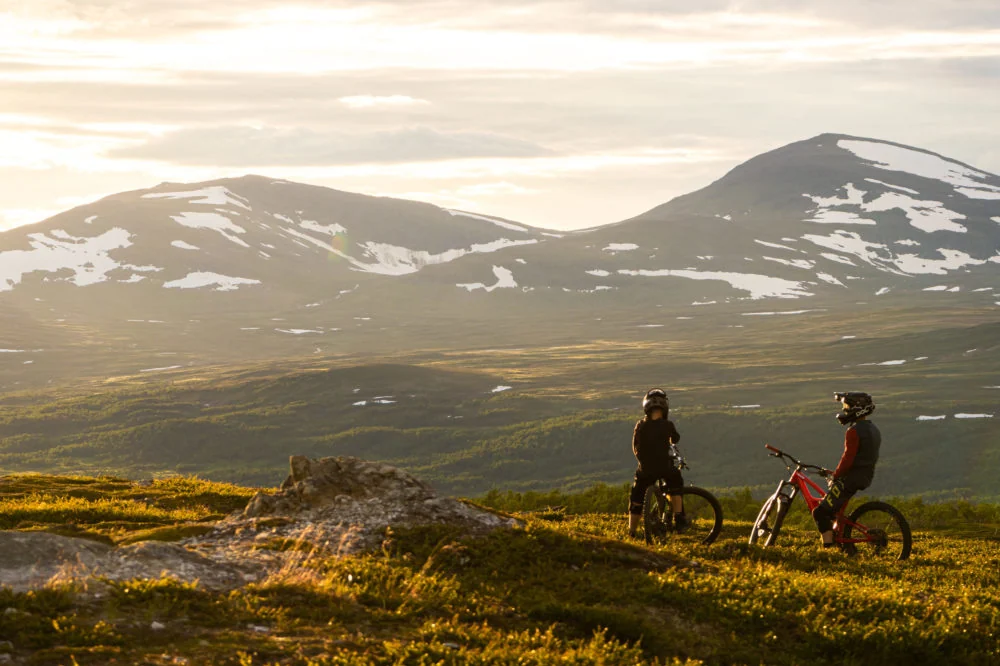 Cyklister blickar ut över fjällen i kvällsljus